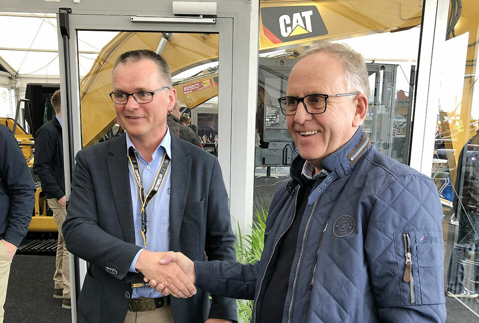 Erik Sollerud og Olav Stangeland gratulerer hverandre med handelen. Stangeland kjøpte de hele 21 CAT gravemaskiner,