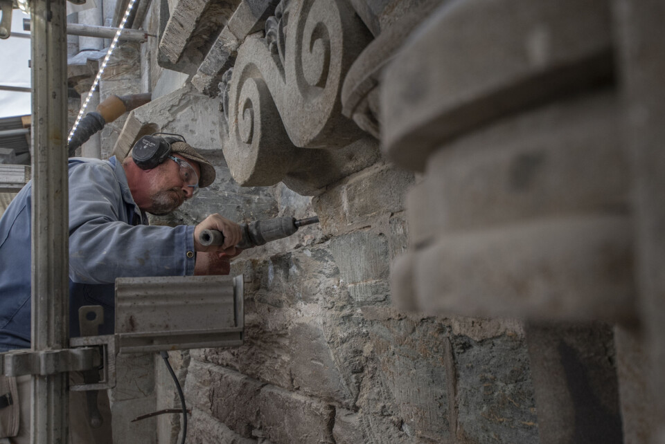 Murer og steinhugger Chris Pennock meisler løs over den rikt utsmykkede Kongeinngangen på Nidarosdomen. Til neste år skal de nyrestaurerte dørene åpne igjen.