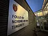 Inngangsparti til Follo og Nordre Østfold tingrett med skilt på veggen i skumring.