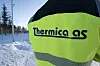 Nærbilde av Thermica AS-logo på gul vernejakke i snødekt terreng. Logistikkbygg