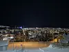 Snødekt småby sett fra høyde en mørk vinterkveld, opplyst av gatelys.