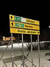 Veiskilt som viser retning mot Kirkenes og Grense Jakobselv en mørk vinterkveld.