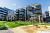 Moderne boligblokker rundt en grønn gårdsplass med lekeplass og gressplener.