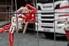 Røde og hvite plastlenker foran en lastebil bak et gjerde.