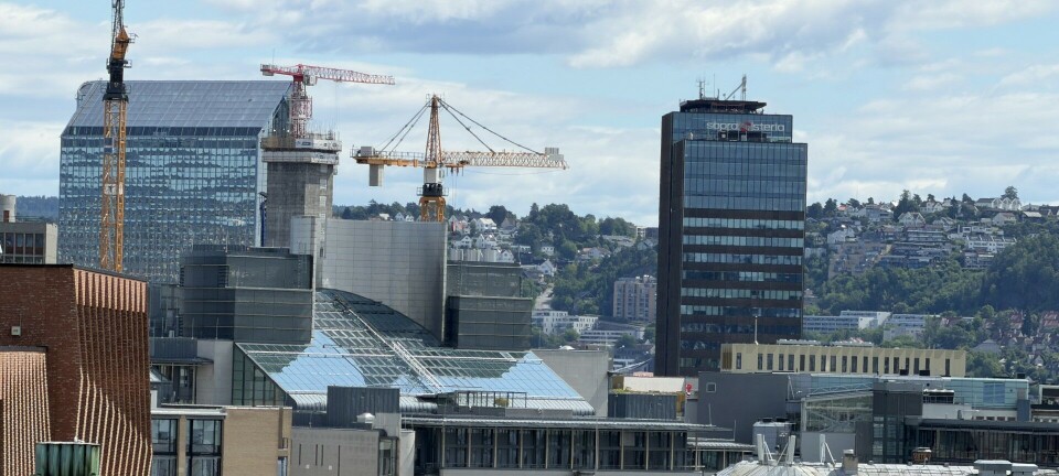 Utsikt over en by med flere kontorbygg, byggekraner og en tett skyline.