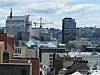 Utsikt over en by med flere kontorbygg, byggekraner og en tett skyline.