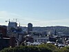 Byutsikt med flere bygninger, to byggekraner og åser i bakgrunnen.