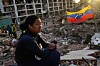 En kvinne sitter på murrester foran en sammenrast bygning, med et venezuelansk flagg i bakgrunnen.