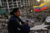 En kvinne sitter på murrester foran en sammenrast bygning, med et venezuelansk flagg i bakgrunnen.