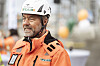 En person i oransje arbeidsklær og hjelm står ute på en byggeplass.