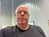En mann sitter innendørs foran lyse vegger i et kontor.