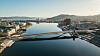 Dronefoto av Bybrua i Drammen som krysser en bred elv mellom byområder og jernbanespor.