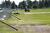Nylagt gress på en fotballbane med en liten traktor i bakgrunnen og gjerder langs siden.