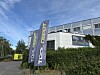 To Tool Depot-flagg står foran et moderne industribygg med hekk og blå himmel.
