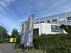To Tool Depot-flagg står foran et moderne industribygg med hekk og blå himmel.