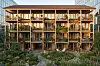 Moderne boligbygg i tre med balkonger, store vinduer og blomstrende hage foran.