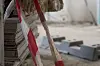 Stablede byggeplater og betongblokker på en byggeplass, med rød- og hvitstripet sperrebånd i forgrunnen.