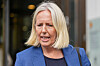 Kvinne med blondt hår og blå blazer står utenfor en bygning.