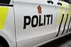 Nærbilde av siden på en hvit politibil med teksten «POLITI» og gule markeringer.