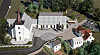 A Modellillustrasjon av en hvit kirke med kirkegård, veier og flere bygninger sett ovenfra.