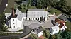 A Modellillustrasjon av en hvit kirke med kirkegård, veier og flere bygninger sett ovenfra.