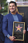 Zac Efron smiler og holder plaketten sin under en seremoni på Hollywood Walk of Fame.