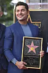 Zac Efron smiler og holder plaketten sin under en seremoni på Hollywood Walk of Fame.