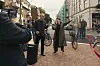 Mennesker samles på et nyanlagt bytorg mellom bygårder, med en rød snor langs høyre side.