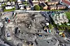 Flyfoto av en stor jernbane byggeplass med utgravninger, anleggsmaskiner og boliger rundt.