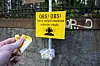 Hånd som holder ørepropper foran et gult skilt med varsel om svært støyende arbeid.