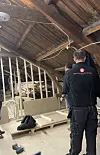 Arbeider med Trestandard Bygg-logo står i et uferdig rom med trekonstruksjoner og verktøy.