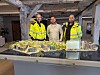Tre personer i arbeidsklær står bak en detaljert modell av et boligområde.