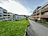 Boligblokker på hver side av en asfaltert gangvei, med et grønt fellesområde mellom bygningene.