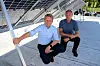 Konsernsjef i Isola Bjørnar Gulliksen og Isola Solar-direktør Anders Besvold Hansen setter seg på skyggesiden av solpanelene sine, men også der produseres det solenergi. Foto: Christian Aarhus